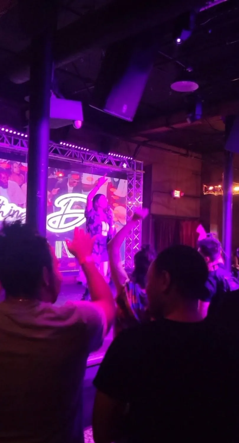 Mother Mystica performing live on stage before a crowd under purple lighting